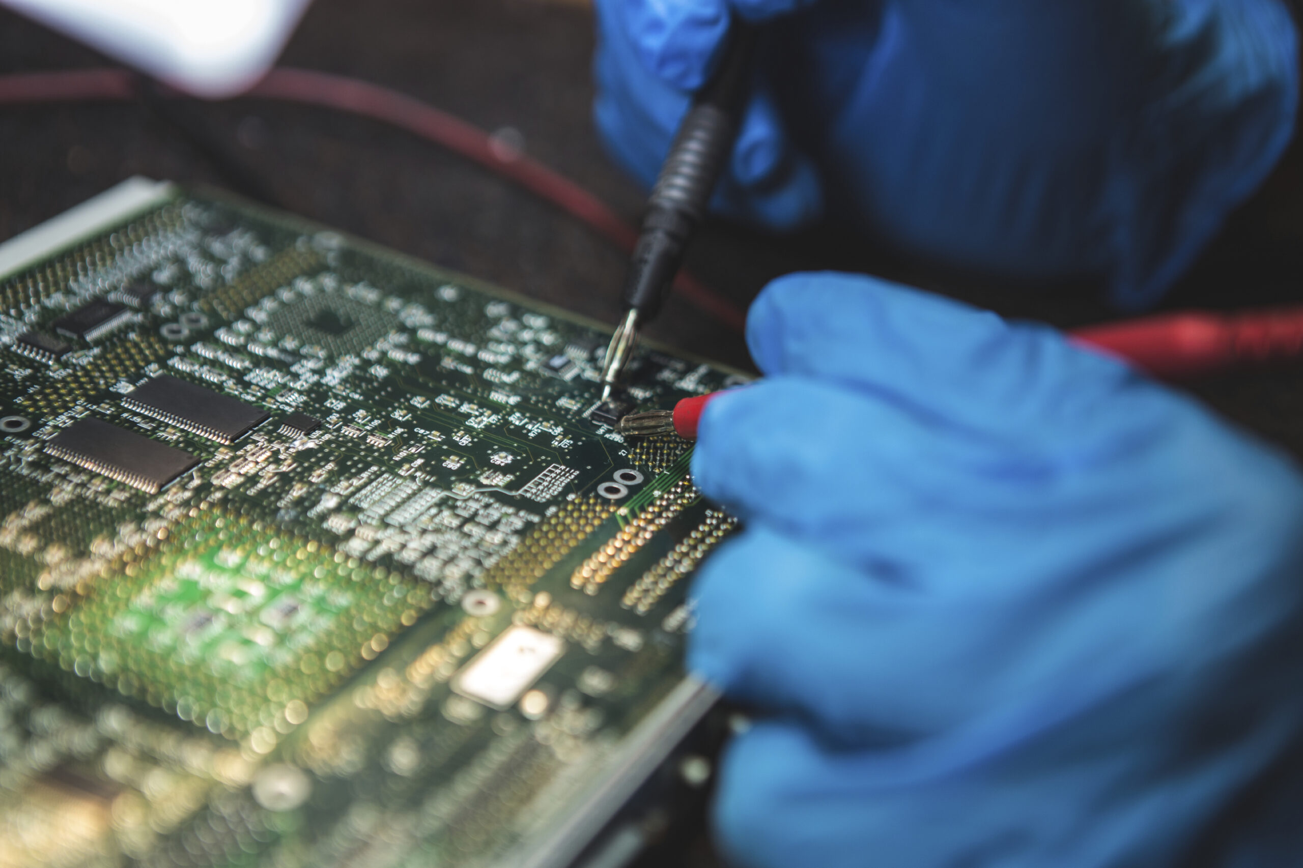 Tests electronic equipment, with protective gloves, in service centre. ( Focus on current clamp ) Tests electronic equipment.